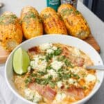 Slow Cooker Mexican Street Corn Soup! Creamy, flavorful fall soup recipe with chicken, corn, potatoes, and a spicy kick. Garnish with bacon, cotija cheese, lime, and cilantro. Easy crockpot soup for a cozy dinner!